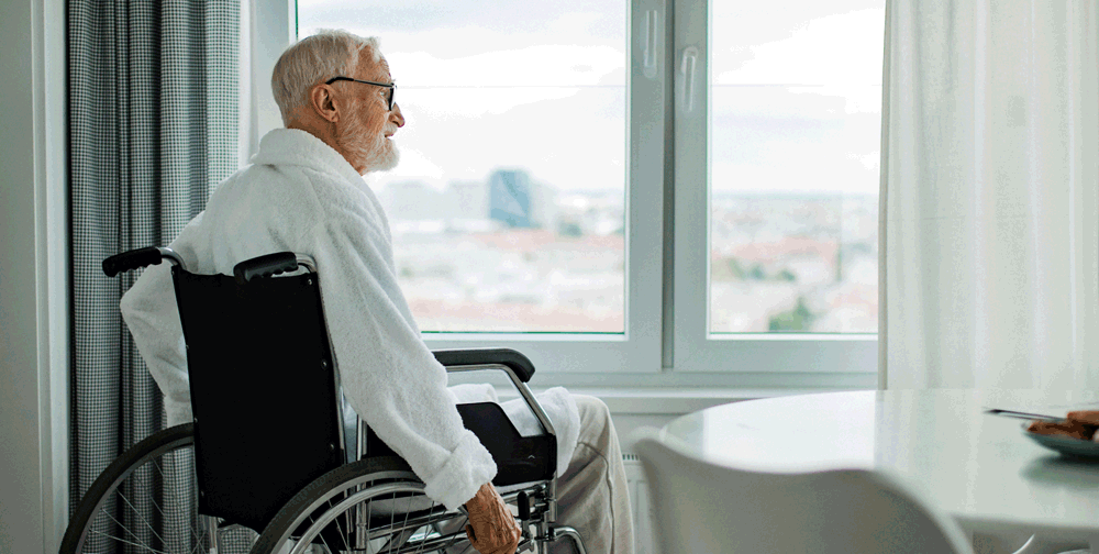 Hombre en silla de ruedas mirando por la ventana