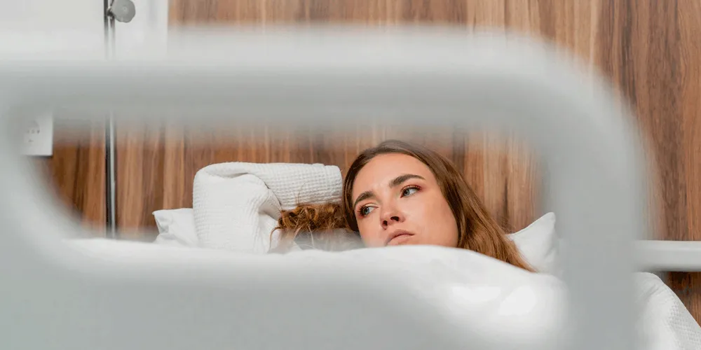 Mujer joven pensativa en la cama de un hospital